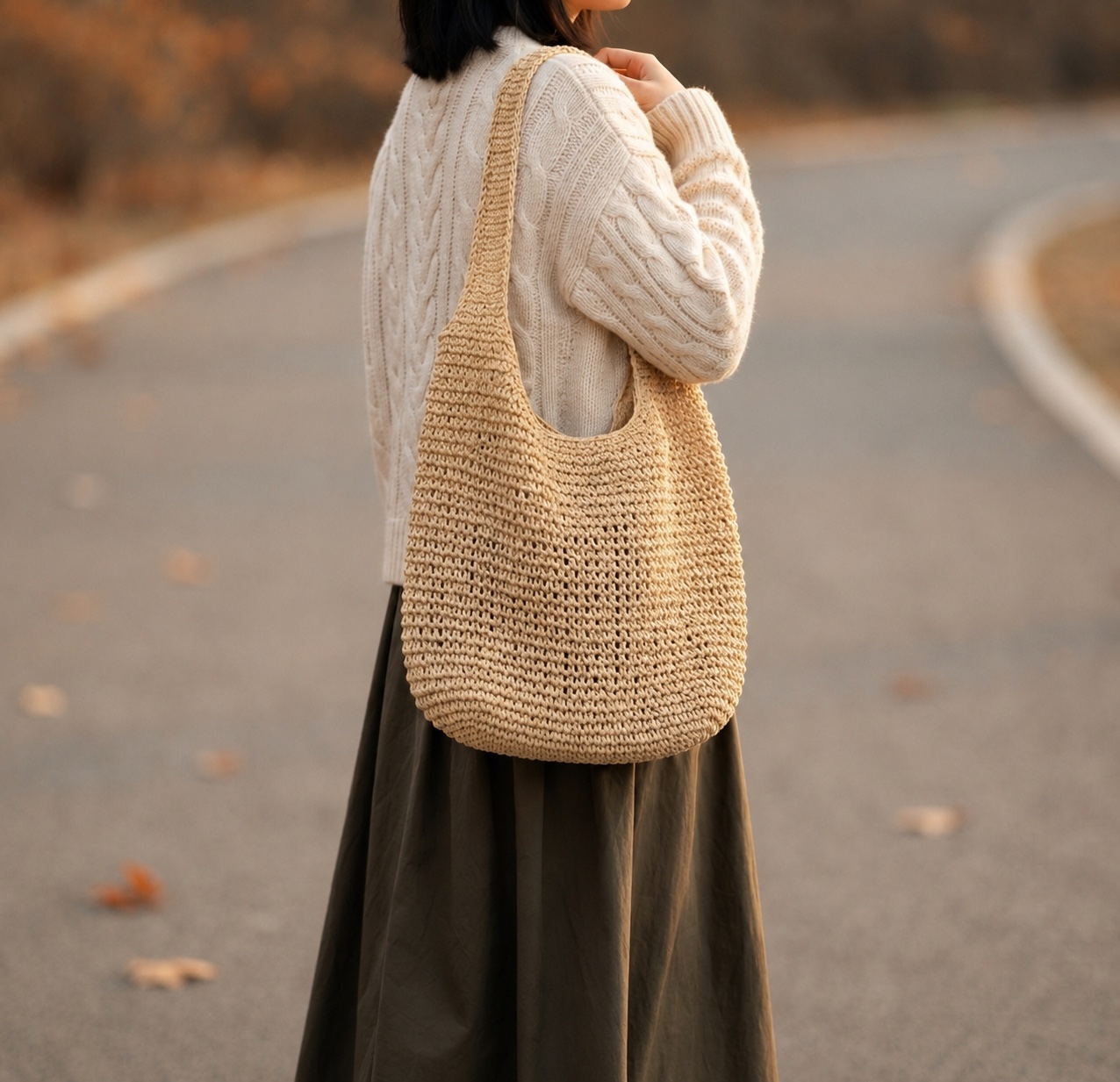 Woman walking through a park in autumn carrying the Foldable Straw Tote Bag
