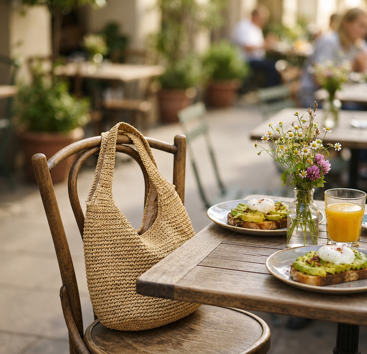 Foldable Straw Tote Bag hanging from the back of a cafe chair