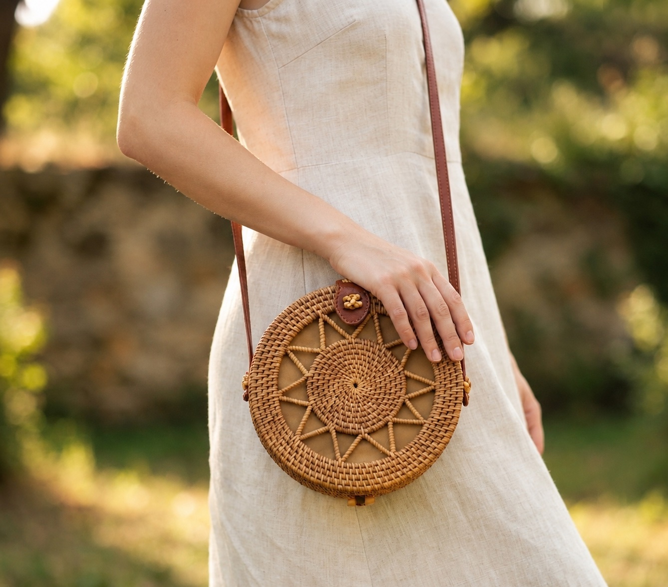Woman standing outdoors wearing the Round Rattan Bag crossbody over a linen dress