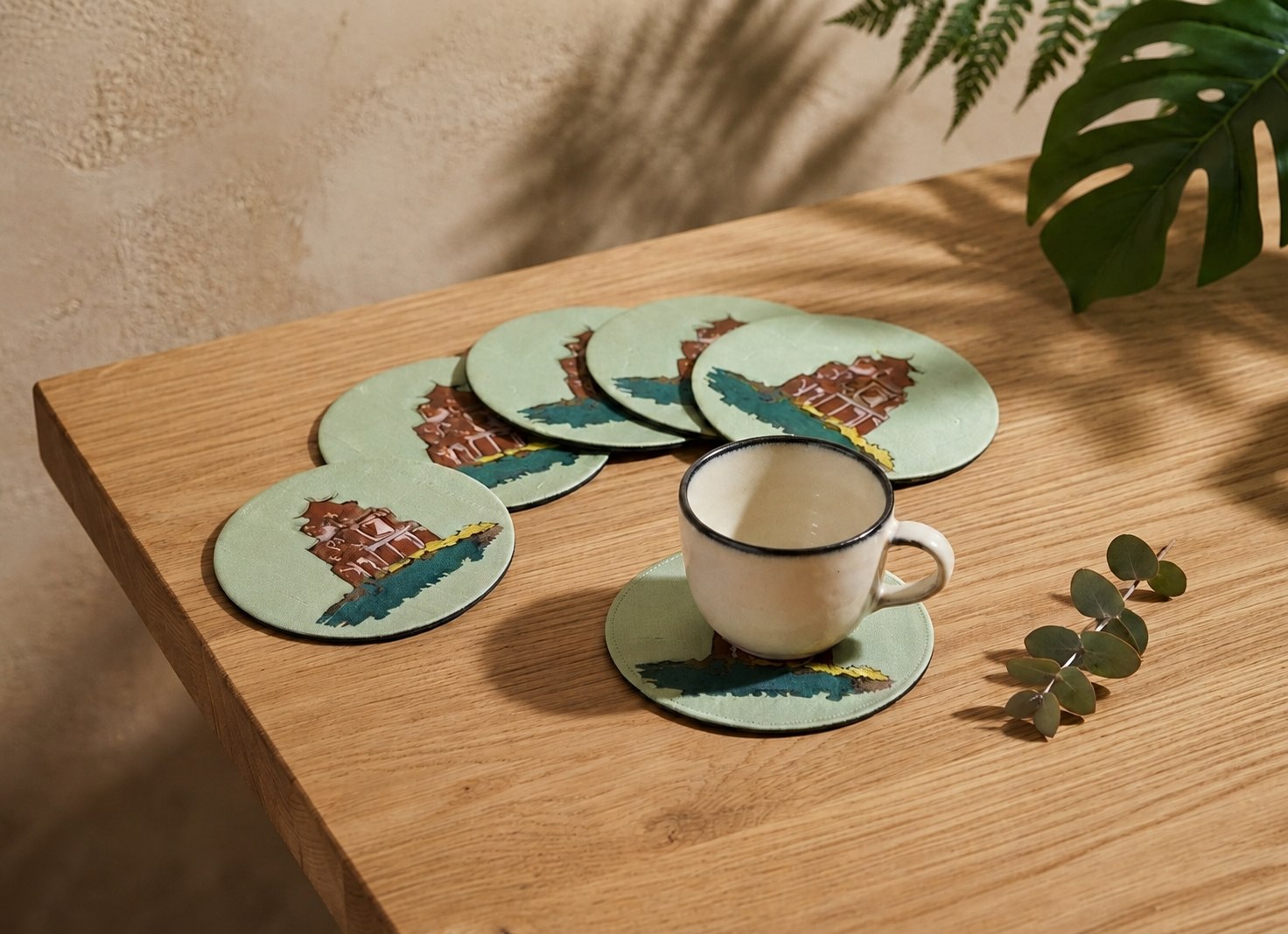 A cup and saucer set on an Upcycled Silk Coaster with a Temple gate design, surrounded by matching coasters on a wooden table