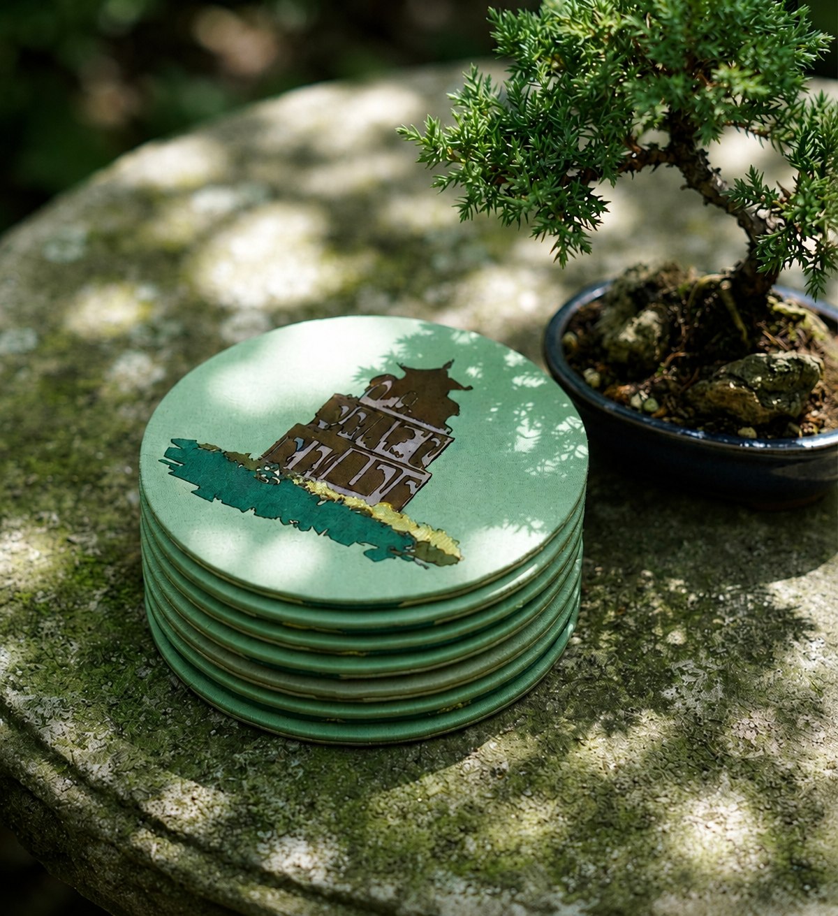 A stack of Upcycled Silk Coasters with a Temple gate design beside a bonsai tree