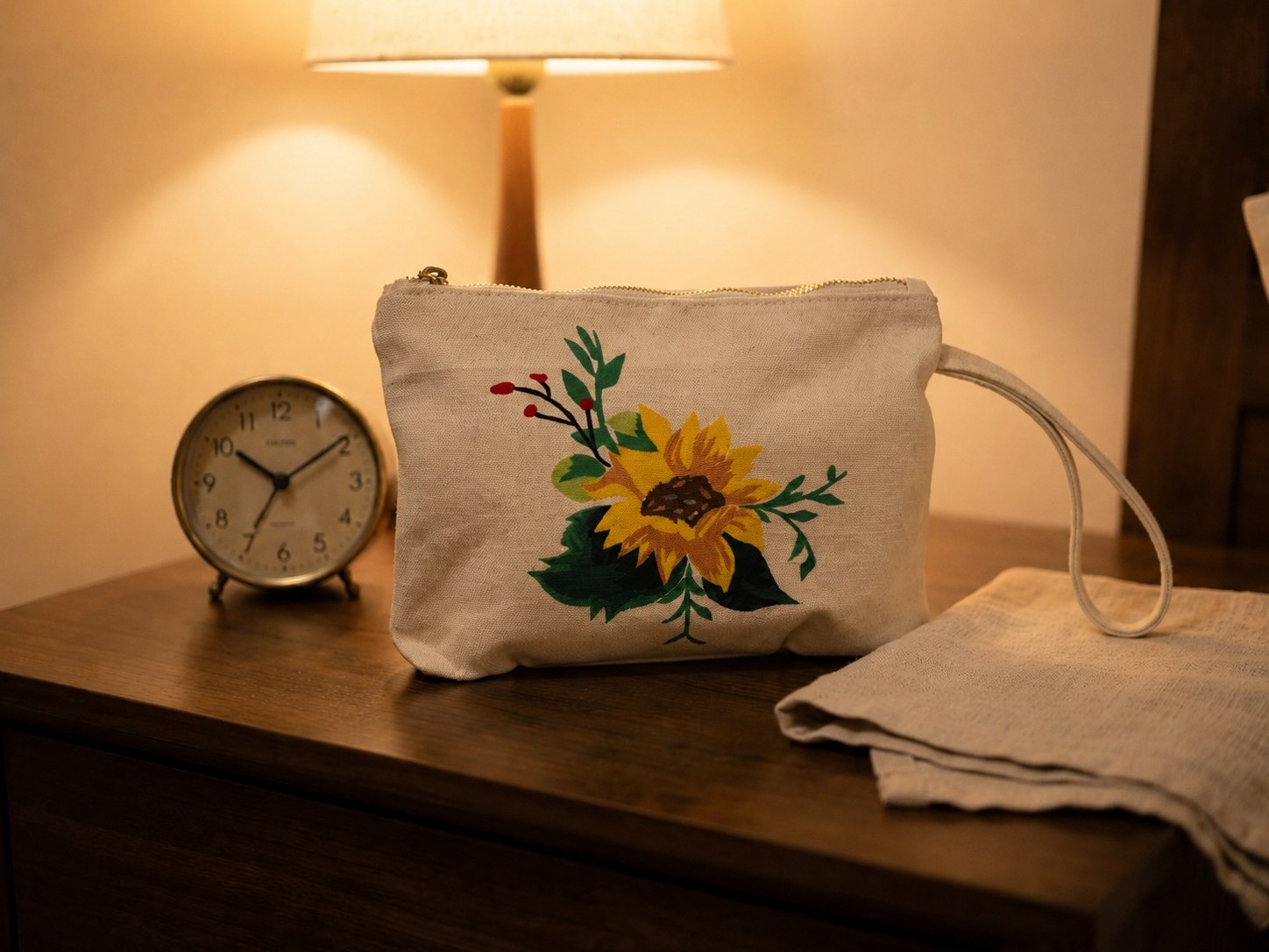 Upcycled Silk Pouch with a sunflower design on a bedside table beside a lamp and alarm clock