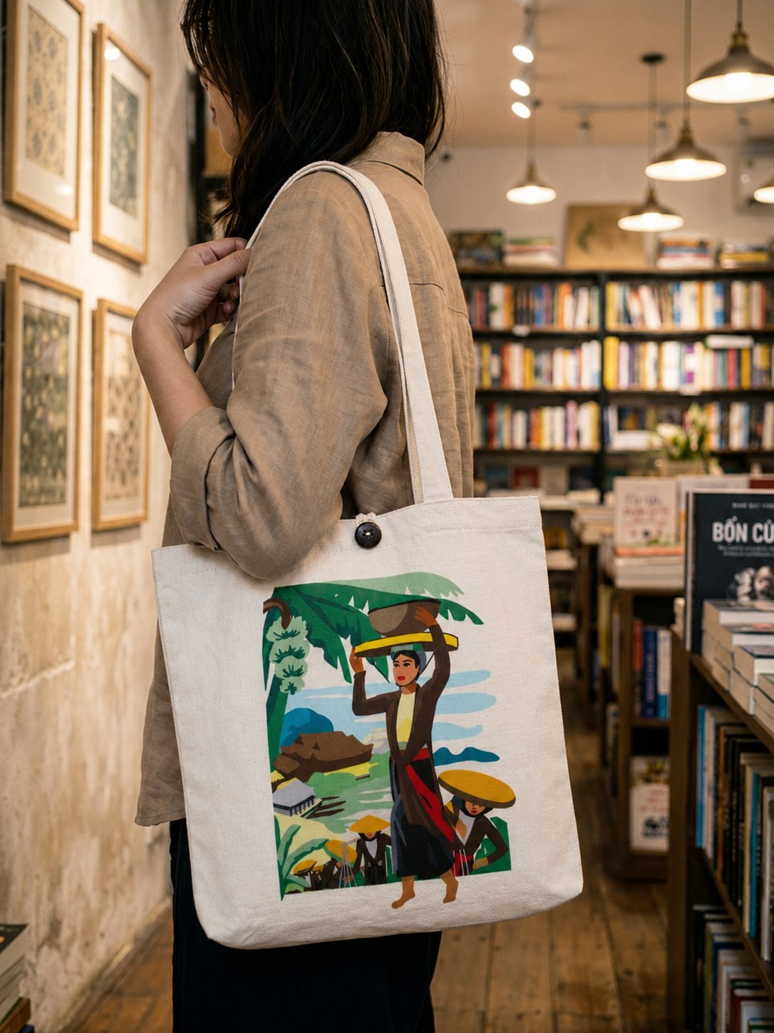 Woman browsing a bookstore with an Upcycled Silk Tote Bag printed with a Vietnamese folk illustration over her shoulder