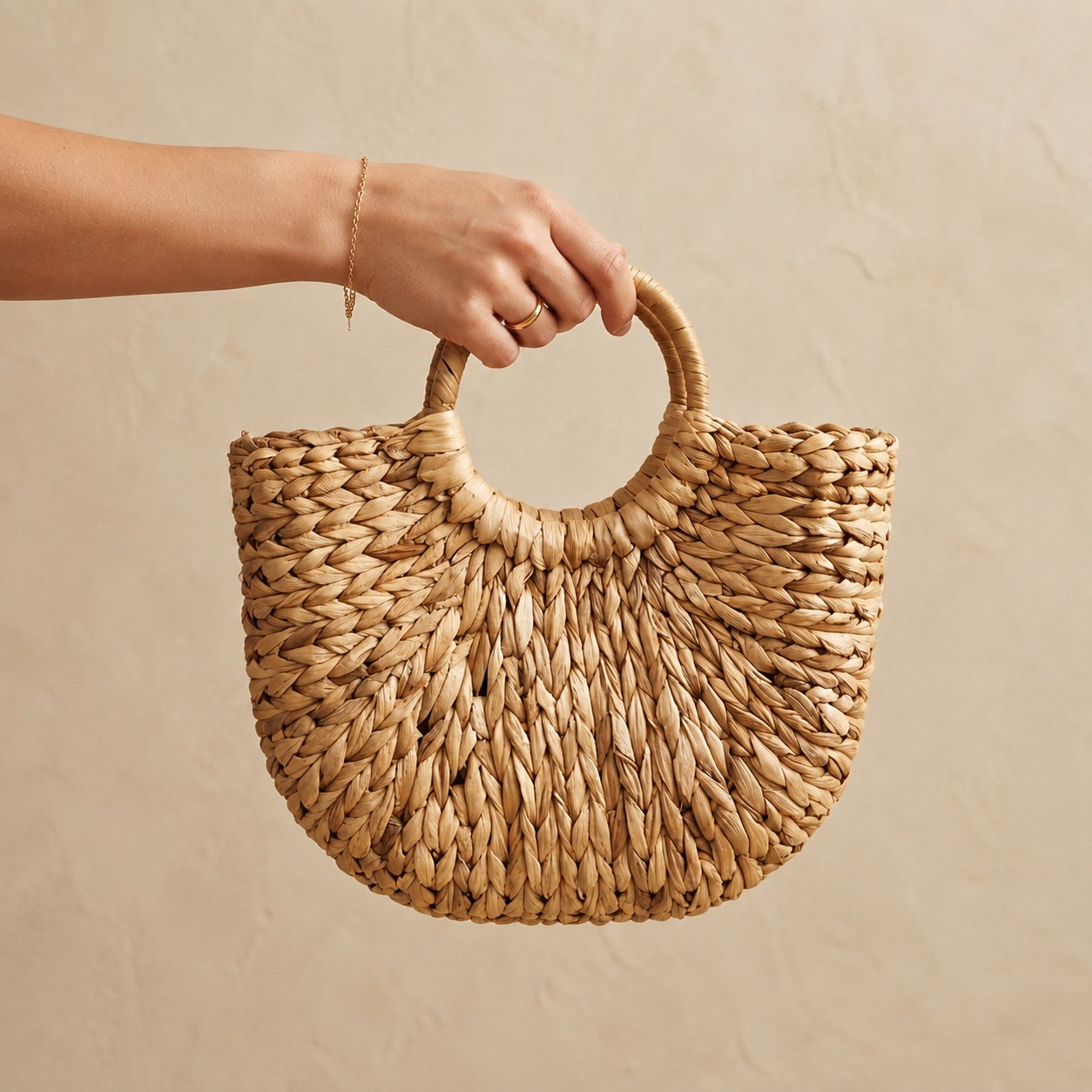 Close-up of a hand holding the Water Hyacinth Handbag by its round handle