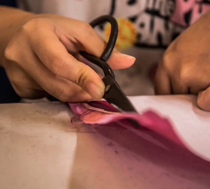 An artisan cutting silk fabric by hand